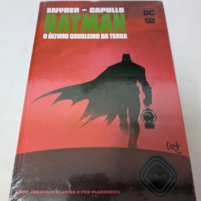 Livro Capa dura BATMAN O ÚLTIMO CAVALEIRO DA TERRA com arte de capa de Batman a segurar lanterna com rosto do Coringa
