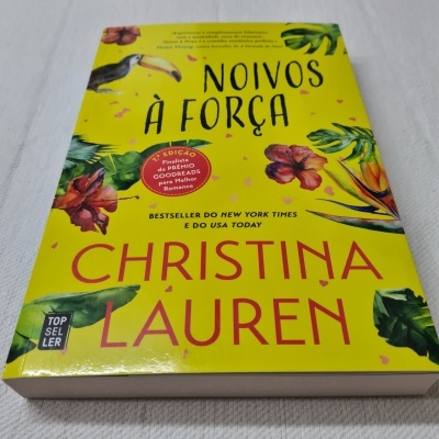 Capa de livro amarelo com flores e texto em preto e vermelho