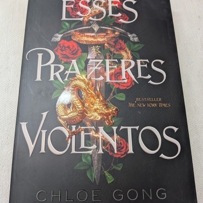 Livro de capa preta com espada, dragão dourado e rosas, título ESSES PRAZERES VIOLENTOS e autor Chloe Gong.