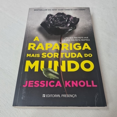 Livro com capa preta, rosa negra e título amarelo com nome da autora em rosa