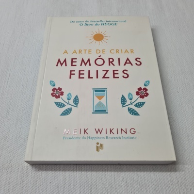 Capa de livro com título 'A Arte de Criar Memórias Felizes' e ilustrações de flores e ampulheta