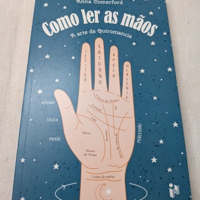 Capa de livro azul com ilustração de mão e texto em português sobre quiromancia