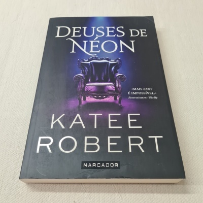 Capa de livro 'DEUSES DE NÉON' de KATEE ROBERT com poltrona roxa ao centro.