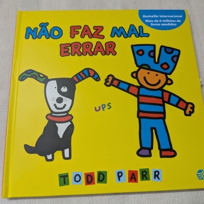 Livro infantil amarelo com cão e criança desenhados, título Não Faz Mal Errar