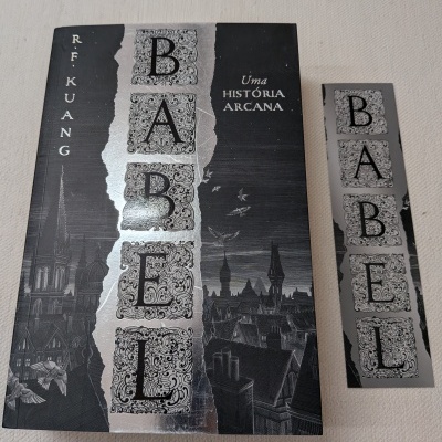 Livro Babel com capa preta e prata e marcador de páginas correspondente