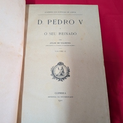 Livro antigo aberto com página de rosto em fundo vermelho.