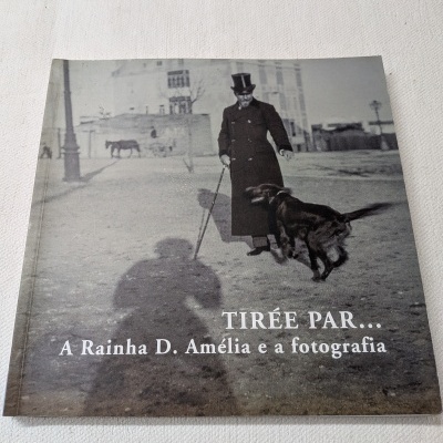 Capa de livro fotográfico a preto e branco com homem a passear cão e texto Tirée Par... A Rainha D. Amélia e a fotografia
