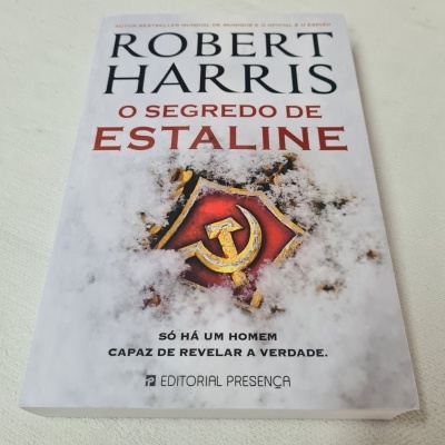 Capa do livro 'O Segredo de Estaline' de Robert Harris com símbolo comunista coberto de neve