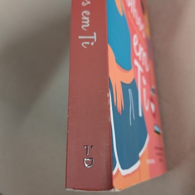 Livro com capa colorida, texto 'De olhos em Ti' na lombada