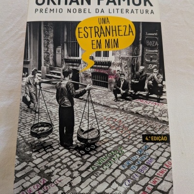 Capa do livro Uma Estranheza em Mim de Orhan Pamuk com imagem a preto e branco de rua de calçada portuguesa