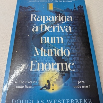 Capa de livro azul com ilustração e título 'Rapariga à Deriva num Mundo Enorme'.