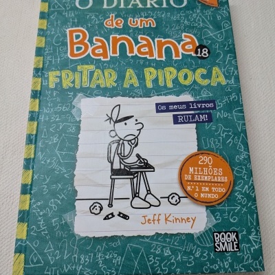 Capa de livro O Diário de um Banana 18 Fritar a Pipoca com ilustração de rapaz a escrever na secretária