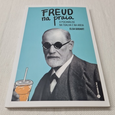 Capa de livro 'FREUD na praia' com imagem de Freud e bebida laranja