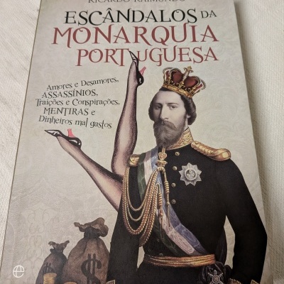 Capa de livro Escândalos da Monarquia Portuguesa com ilustração de homem com coroa e pernas femininas levantadas.