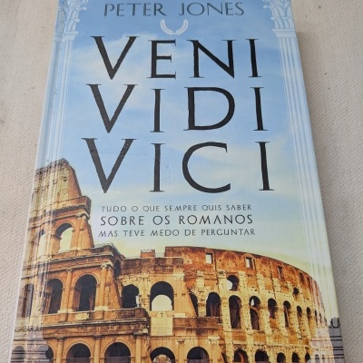 Capa de livro azul com colunas, Coliseu e texto VENI VIDI VICI.