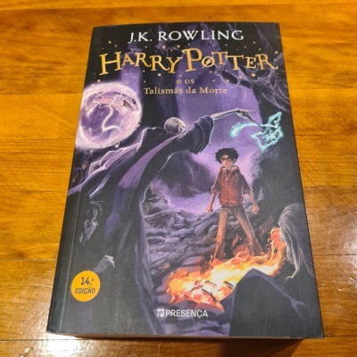 Capa do livro Harry Potter e os Talismãs da Morte sobre mesa de madeira