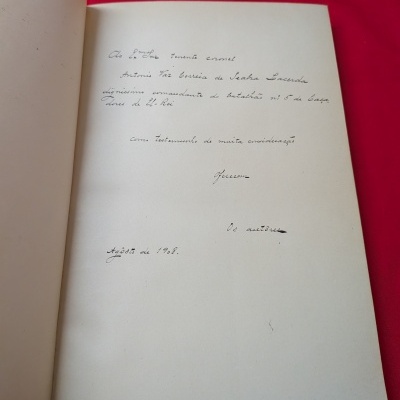 Página com dedicatória manuscrita em livro antigo sobre fundo vermelho