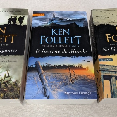 Três livros de capa colorida de Ken Follett em português alinhados sobre uma superfície clara