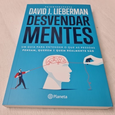 Livro 'Desvendar Mentes' de David J. Lieberman com capa azul e ilustração de cabeça humana e fio vermelho