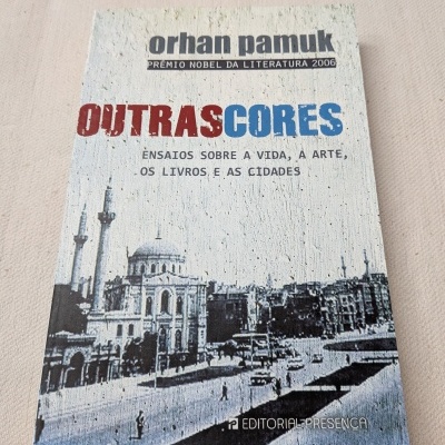 Capa de livro Outras Cores de Orhan Pamuk com imagem de cidade e texto na capa