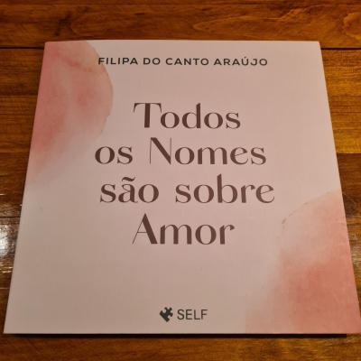 Livro 'Todos os Nomes são sobre Amor' com capa branca e detalhes rosa.