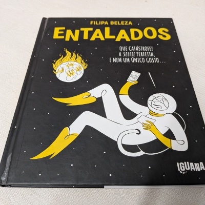 Capa de livro preta com ilustração de astronauta e fogo, texto em amarelo e branco