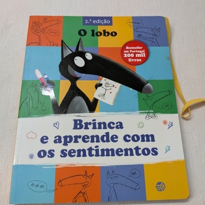 Livro infantil sobre sentimentos com ilustração de um lobo preto na capa colorida.