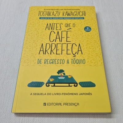Capa do livro amarelo com título e ilustração de pessoa numa mesa a beber café.
