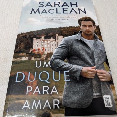 Capa de livro com homem de casaco cinza e castelo ao fundo, título UM DUQUE PARA AMAR de Sarah MacLean