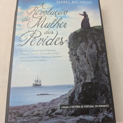Capa de livro com mulher em falésia segurando lâmpada e navio ao longe no mar