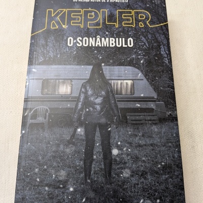Capa de livro KEPLER O SONÂMBULO com figura de costas segurando machado a frente de caravana