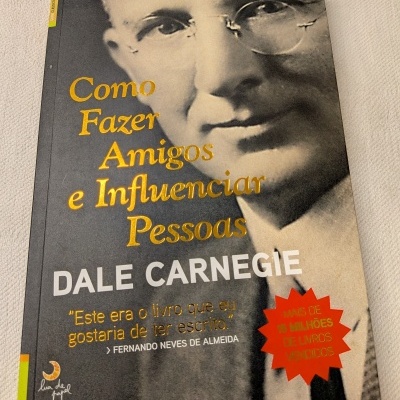 Livro Como Fazer Amigos e Influenciar Pessoas de Dale Carnegie com capa em tons cinzentos e dourado