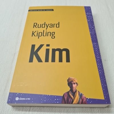 Capa do livro Kim de Rudyard Kipling com fundo amarelo e detalhe roxo com foto de homem com turbante
