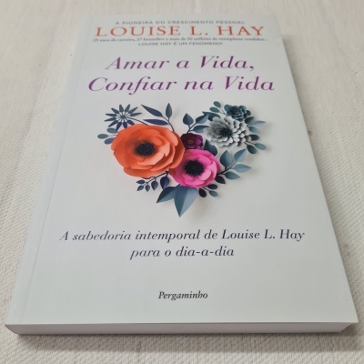 Livro 'Amar a Vida, Confiar na Vida' de Louise L. Hay com capa branca e flores coloridas