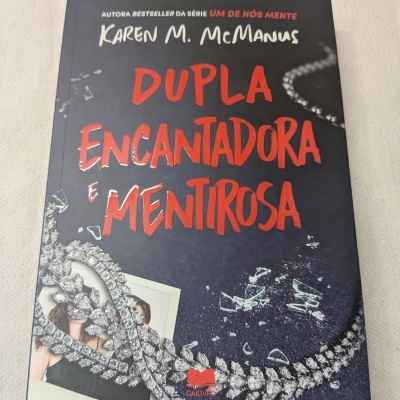 Capa do livro Dupla Encantadora e Mentirosa de Karen M. McManus com colar brilhante e vidro partido