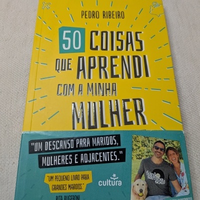 Capa de livro amarelo e verde com título e citações em português e foto de casal com cão