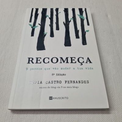 Livro RECOMEÇA com capa branca e ilustração de árvores pretas