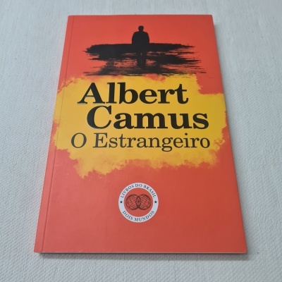 Capa do livro 'Albert Camus O Estrangeiro' vermelha com texto amarelo e preto