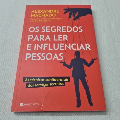 Capa de livro vermelha com texto e silhueta de homem controlado por cordas