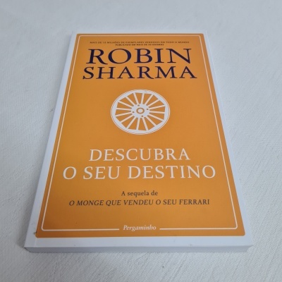 Livro laranja 'Descubra o seu destino' com texto em preto e branco