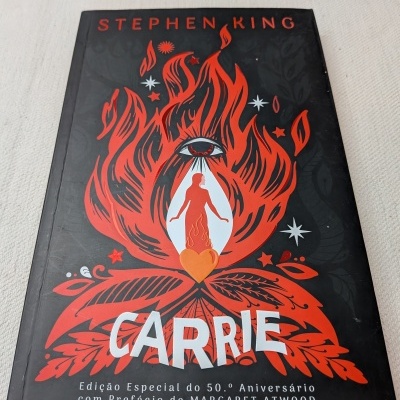 Capa do livro Carrie de Stephen King com ilustração vermelha e texto branco em fundo preto.