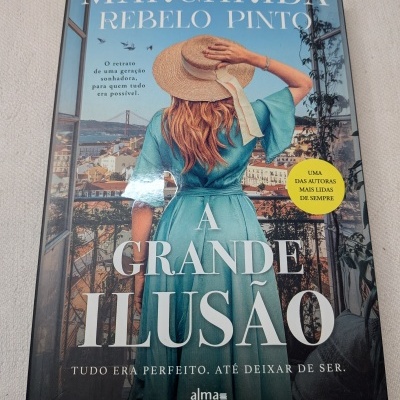 Livro A Grande Ilusão de Margarida Rebelo Pinto com imagem de mulher de costas em vestido azul e chapéu de palha