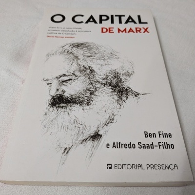 Capa de livro 'O CAPITAL DE MARX' com desenho de rosto e texto em branco e preto