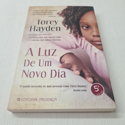 Capa de livro 'A Luz De Um Novo Dia' com retrato de criança e texto sobre autor e edição.