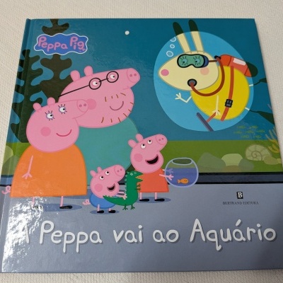 Capa de livro infantil da Peppa Pig com fundo azul e personagens à frente de um aquário