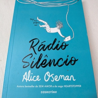 Livro Rádio Silêncio de Alice Oseman com capa azul e ilustração de pessoa ligada a laptop.