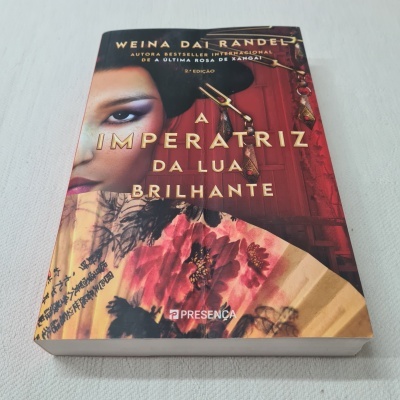 Capa do livro A IMPERATRIZ DA LUA BRILHANTE com rosto feminino e leque floral
