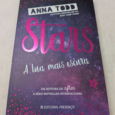 Capa de livro Stars A lua mais escura com fundo estrelado e texto em rosa metálico.