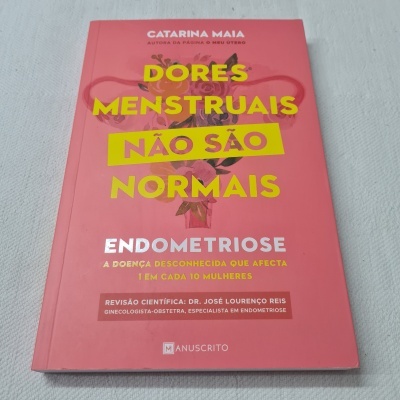Livro rosa intitulado 'Dores Menstruais Não São Normais Endometriose' sobre superfície branca