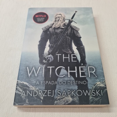 Capa do livro 'The Witcher A Espada do Destino' com imagem de homem armado e selo Netflix